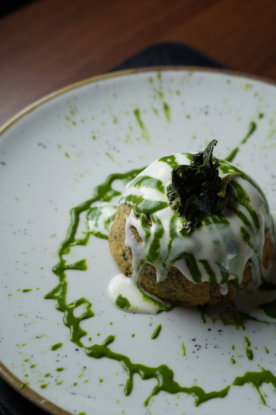 Lo stesso sformato visto dall'alto su un piatto puntinato, con una scia di salsa verde tutto intorno