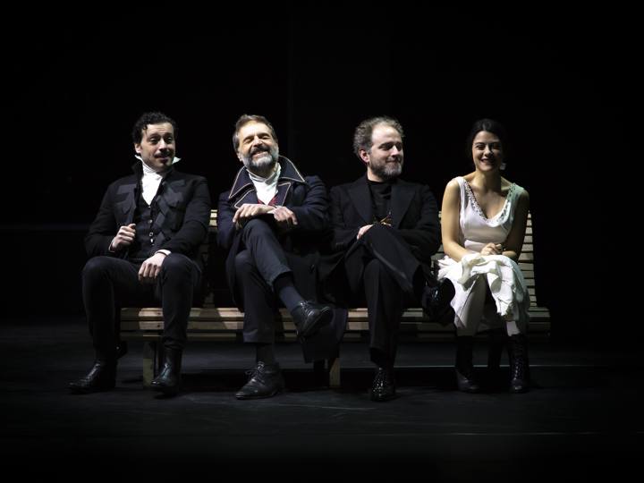 Quattro personaggi seduti su una panchina in scena