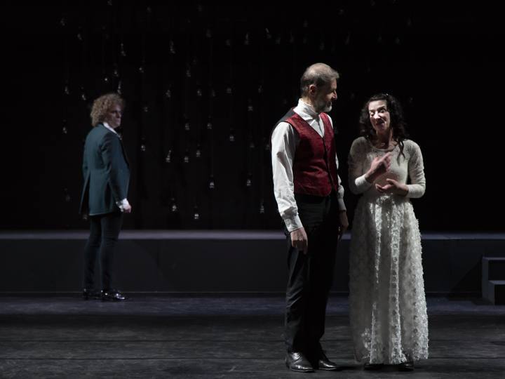 Tre personaggi in scena con le lampadine sullo sfondo